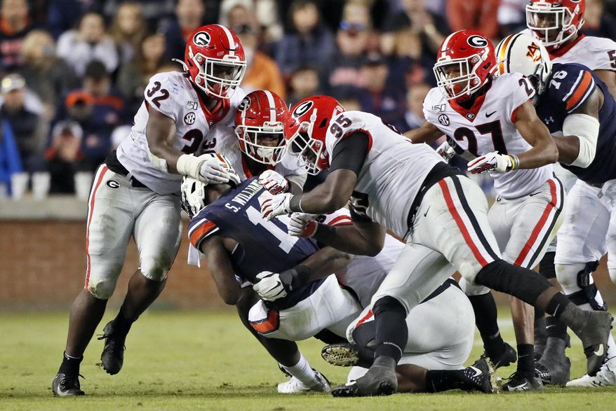 Georgia defenders, including linebacker Monty Rice (32), defensive lineman Devonte Wyatt (95), defensive back Eric Stokes (27) and linebacker Tae Crowder (30) swarm Auburn wide receiver Shedrick Jackson (11) during an NCAA college football game, Saturday, Nov. 16, 2019, in Auburn, Ala. Georgia won 21-14. (Bob Andres/Atlanta Journal-Constitution via AP)