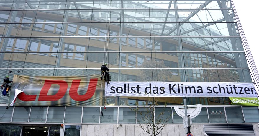 Greenpeace activists remove the 'C' of the short form 'CDU' for 'Christian Democratic Union' to create the slogan 'DU sollst das Klima schützen' ('YOU should protect the climate') during a protest at German Chancellor Angela Merkel's CDU party headquarters in Berlin, Germany, Thursday, Nov. 21, 2019. (AP Photo/Michael Sohn)