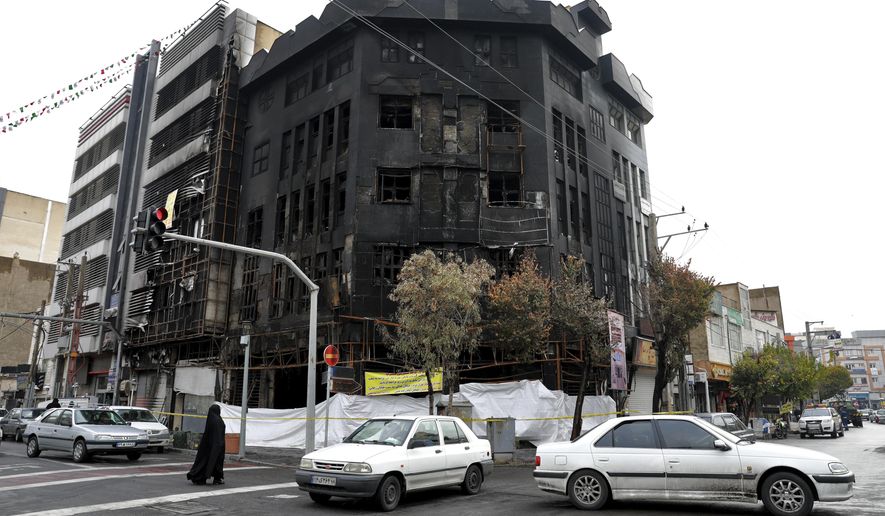 Traffic passes a building that was set ablaze during recent protests over government-set gasoline prices rises, in Tehran, Iran, Wednesday, Nov. 20, 2019. The demonstrations struck at least 100 cities and towns, spiraling into violence that saw banks, stores and police stations attacked and burned. (AP Photo/Ebrahim Noroozi)