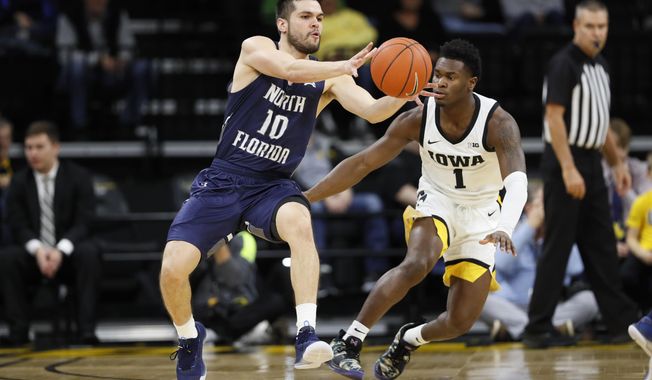 North Florida guard Ivan Gandia-Rosa (10) passes in front of Iowa guard Joe Toussaint (1) during the first half of an NCAA college basketball game, Thursday, Nov. 21, 2019, in Iowa City, Iowa. (AP Photo/Charlie Neibergall)