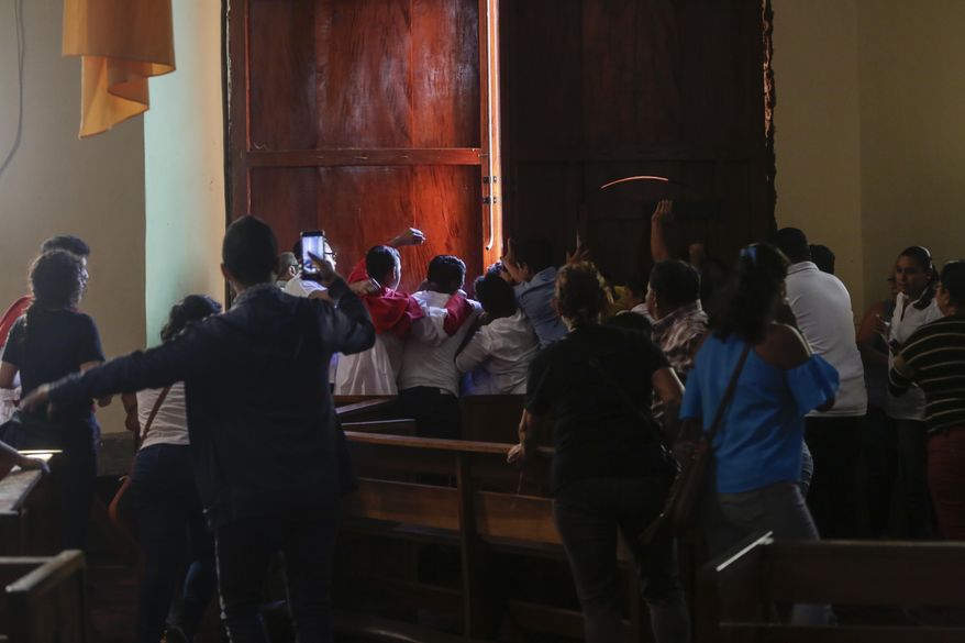 Parishioners and altar boys repel supporters of President Daniel Ortega who are trying to enter the San Juan Bautista Church by force, in Masaya, Nicaragua, Thursday, Nov. 21, 2019. The pro-Ortega group disrupted a mass in support of a group of mothers who are engaged in a hunger strike at the San Miguel Church in Masaya, to demand the release of their sons and daughters who are imprisoned by the Ortega government. (AP Photo/Alfredo Zuniga)
