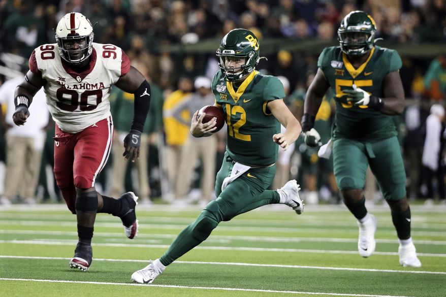 Baylor quarterback Charlie Brewer (12) carries the ball as he is chased by Oklahoma defensive lineman Neville Gallimore (90) during the first half of an NCAA college football game in Waco, Texas, Saturday, Nov. 16, 2019. (AP Photo/Ray Carlin)
