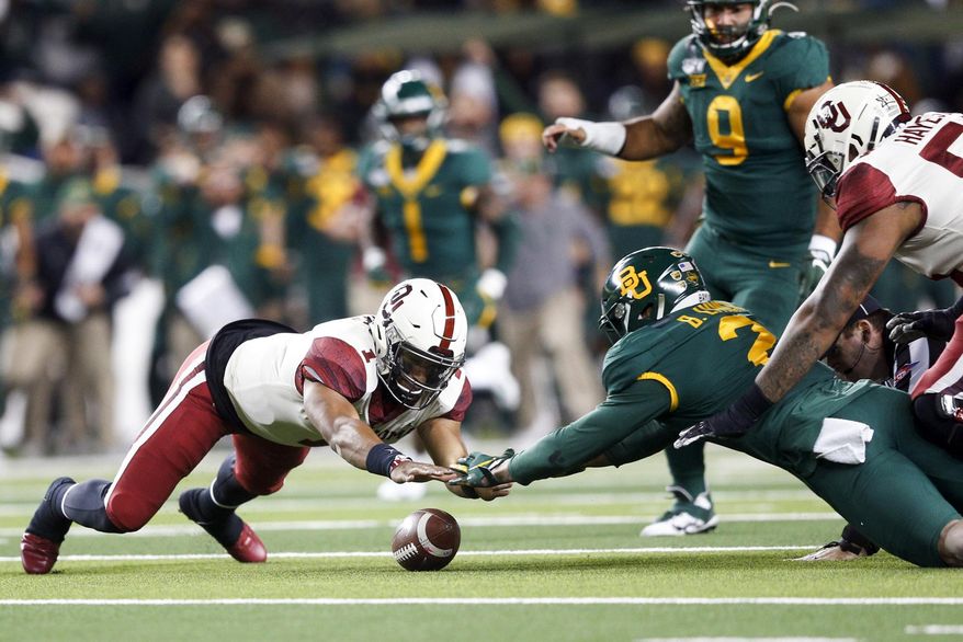 Oklahoma quarterback Jalen Hurts (1) and Baylor linebacker Blake Lynch (2) dive to recover a fumble during an NCAA college football game, in Waco, Texas, Saturday, Nov. 16, 2019. (Ian Maule/Tulsa World via AP)
