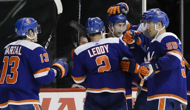 New York Islanders&#x27; Mathew Barzal (13), Nick Leddy (2) and Johnny Boychuk (55) celebrate with Brock Nelson after Nelson scored the game winning goal during the overtime period of an NHL hockey game against the Pittsburgh Penguins Thursday, Nov. 21, 2019, in New York. The Islanders won 4-3. (AP Photo/Frank Franklin II)