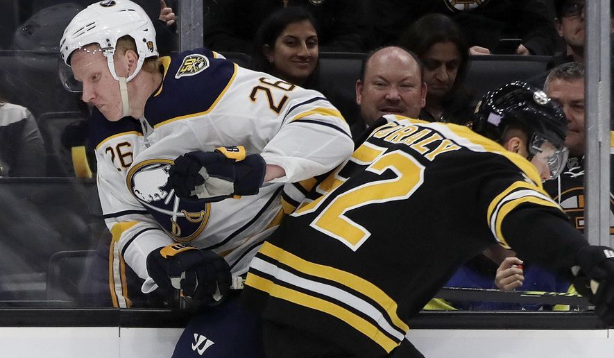 Buffalo Sabres defenseman Rasmus Dahlin (26) and Boston Bruins center Sean Kuraly (52) crash along the boards during the first period of an NHL hockey game Thursday, Nov. 21, 2019, in Boston. (AP Photo/Elise Amendola)
