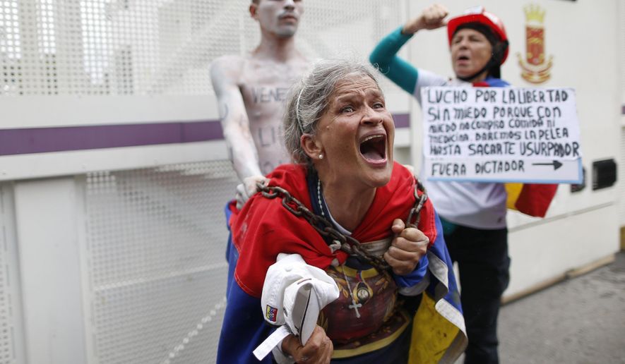 A woman screams in front a metal screen barrier set by National Police to block a university students' protest calling on the military to abandon President Nicolas Maduro and join their fight to end the nation's historic crisis in Caracas, Venezuela, Thursday, Nov. 21, 2019. (AP Photo/Ariana Cubillos)