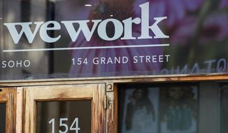FILE - This Oct. 15, 2019, file photo shows a WeWork logo at the entrance to one of their office spaces in the SoHo neighborhood of New York. WeWork is slashing nearly 20% of its work force in the wake of its failed stock market debut.  The shared-office company said it has laid off 2,400 of its approximately 12,500 employees to “create a more efficient organization.”  (AP Photo/Mary Altaffer, File)