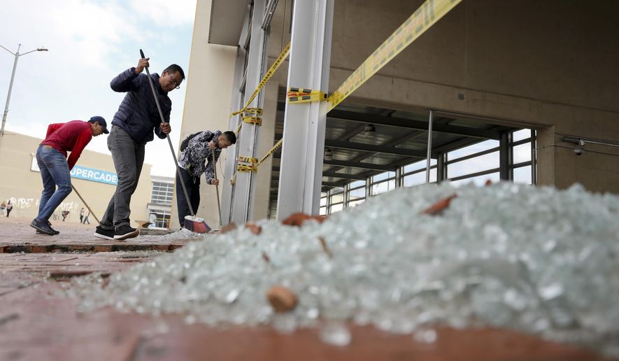Workers clear broken glass from a bus station damaged by anti-government demonstrators, in Bogota, Colombia, Friday, Nov. 22, 2019. Protesters attacked the station Thursday during a nationwide strike called by labor unions, students and teachers to protest everything from economic inequality to violence against social leaders. (AP Photo/Fernando Vergara)