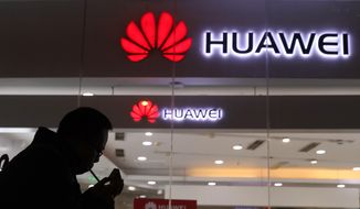 In this Dec. 6, 2018, photo, a man lights a cigarette outside a Huawei retail shop in Beijing. The Federal Communications Commission on Friday, Nov. 22, 2019, voted, 5-0, to bar U.S. telecommunications providers from using government subsidies to pay for networking equipment from companies that are a threat to national security. The agency says China’s Huawei and ZTE pose such a threat. (AP Photo/Ng Han Guan) **FILE**