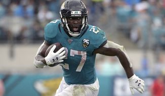 FILE - In this Oct. 27, 2019, file photo, Jacksonville Jaguars running back Leonard Fournette (27) rushes for yardage against the New York Jets during the first half of an NFL football game, in Jacksonville, Fla. Fournette had a series of meetings and calls this week after carrying the ball a season-low eight times in a 20-point loss to Indianapolis. The most notable of them was chatting with 1981 Heisman Trophy winner and retired Oakland Raiders star Marcus Allen, who told the third-year pro about his experience having to play fullback and share a backfield with fellow Heisman winner Bo Jackson more than 30 years ago. “His situation was harder than mine,” said Fournette, who first met Allen during a recruiting visit to USC while he was in high school.(AP Photo/Phelan M. Ebenhack, File)