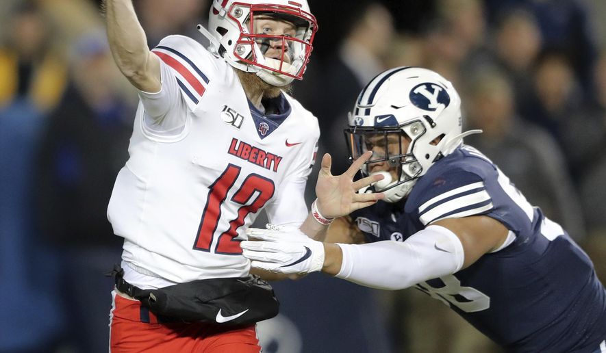 Liberty quarterback Stephen Calvert (12) throws a pass as he is hit by BYU defensive lineman Uriah Leiataua (58) during an NCAA college football Saturday, Nov. 9, 2019, in Provo, Utah. BYU won 31-24. (Scott G Winterton/The Deseret News via AP)