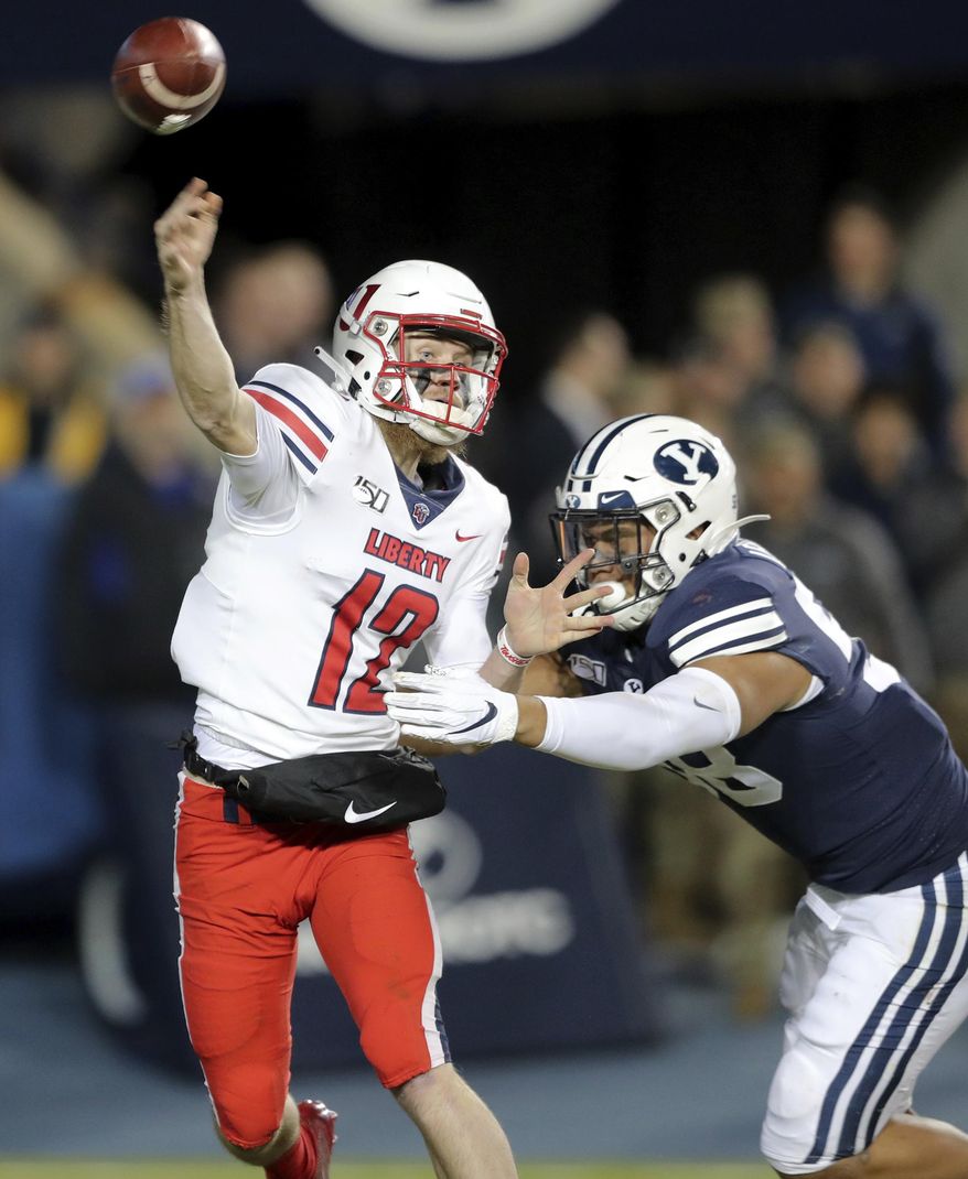 Liberty quarterback Stephen Calvert (12) throws a pass as he is hit by BYU defensive lineman Uriah Leiataua (58) during an NCAA college football Saturday, Nov. 9, 2019, in Provo, Utah. BYU won 31-24. (Scott G Winterton/The Deseret News via AP)
