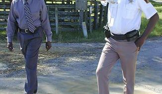 In this March 21, 2000 photo, Lowndes County Sheriff Willie Vaughner, left, and chief deputy John Williams stand at the intersection where Williams apprehended Jamil Abdullah Al-Amin on Monday evening in White Hall, Ala. Williams was fatally shot in the line of duty Saturday evening, Nov. 23, 2019, in a county near the state capital city, Alabama Gov. Kay Ivey said. Ivey tweeted that Lowndes County Sheriff Williams was “a pillar of the community.”  (Al Benn/Montgomery Advertiser via AP)