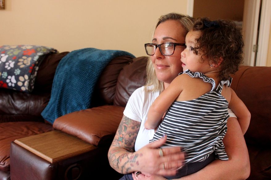 In this Nov. 6, 2019 photo, Nicole Desimone holds her 18-month old daughter Kelon Mickens in her home in Palm Coast, Fla. Desimone is facing challenges since getting sober two years ago, which include, getting a home, finding a job that pays enough to cover her bills, and, recently, a long legal battle to regain custody of her two youngest children, who now live with her. (Nikki Ross/The Daytona Beach News-Journal via AP)