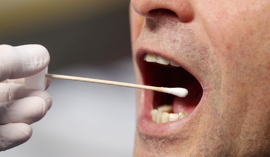 A police officer poses to illustrate a saliva test in Grevenbroich, Germany, Saturday, Nov. 23, 2019. Police in the western German city of Grevenbroich have asked about 900 men to come forward and have their DNA tested to help solve the gruesome killing of an 11-year-old girl decades ago. The girl, Claudia Ruf, was kidnapped, raped and choked to death by an anonymous murderer in 1996. (Roland Weihrauch/dpa via AP)