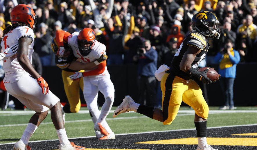 Iowa running back Tyler Goodson, right, scores on a 2-yard touchdown run ahead of Illinois defensive back Stanley Green, left, during the first half of an NCAA college football game, Saturday, Nov. 23, 2019, in Iowa City, Iowa. (AP Photo/Charlie Neibergall)