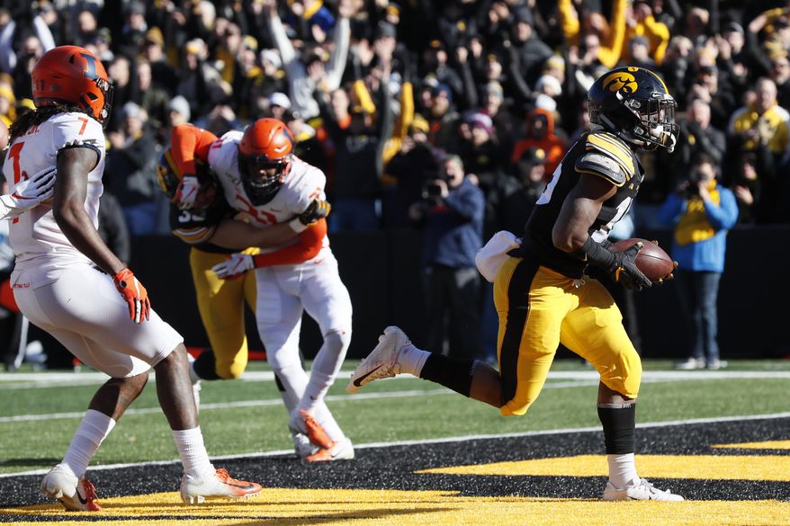Iowa running back Tyler Goodson, right, scores on a 2-yard touchdown run ahead of Illinois defensive back Stanley Green, left, during the first half of an NCAA college football game, Saturday, Nov. 23, 2019, in Iowa City, Iowa. (AP Photo/Charlie Neibergall)