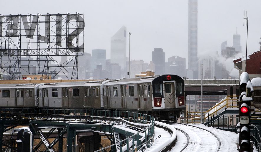 Part of the Manhattan skyline can be seen as a Flushing-bound 7 train arrives at Queensboro Plaza station after limited subway service was restored following a winter storm, Tuesday, Jan. 27, 2015, in the Queens borough of New York. Gov. Andrew Cuomo says a snowstorm-related New York City area travel ban is lifted, except for Suffolk County on Long Island. (AP Photo/Jason DeCrow)