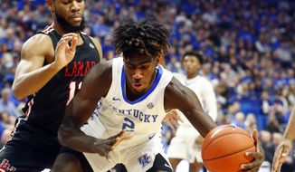 Kentucky&#x27;s Kahlil Whitney (2) looks for an opening in the defense of Lamar&#x27;s V.J. Holmes, left, during the first half of an NCAA college basketball game in Lexington, Ky., Sunday, Nov. 24, 2019. (AP Photo/James Crisp)