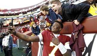 Washington Redskins quarterback Dwayne Haskins takes selfies with fans during the second half of an NFL football game against the Detroit Lions, Sunday, Nov. 24, 2019, in Landover, Md. The Redskins won 19-16. (AP Photo/Patrick Semansky)