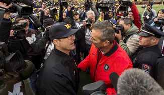 FILE - In this Nov. 25, 2017, file photo, Michigan head coach Jim Harbaugh, center left, shakes hands with Ohio State head coach Urban Meyer, center right, after Ohio State defeated Michigan 31-20 in an NCAA college football game in Ann Arbor, Mich. Jim Harbaugh’s job is safe at Michigan whether he finally beats Ohio State or falls to 0-5, but the timing for a win would provide a boost for college football’s winningest program. (AP Photo/Tony Ding, File)