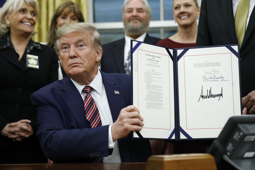 President Donald Trump displays the Preventing Animal Cruelty and Torture Act after signing it during a ceremony in the Oval Office of the White House, Monday, Nov. 25, 2019, in Washington. (AP Photo/Patrick Semansky)
