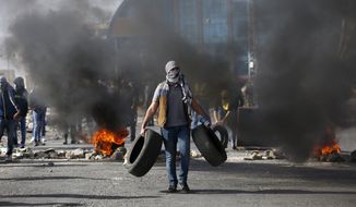 Palestinian demonstrators burn tires as they clash with Israeli troops during the protest against the U.S. announcement that it no longer believes Israeli settlements violate international law., at checkpoint Beit El near the West Bank city of Ramallah, Tuesday, Nov. 26, 2019, (AP Photo/Majdi Mohammed)