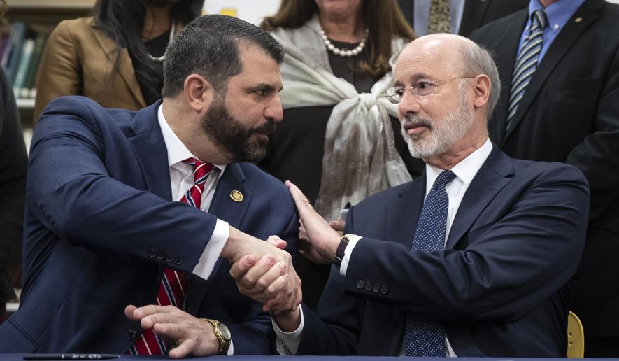 Pennsylvania Gov. Tom Wolf, right, shakes hands with Rep. Mark Rozzi, D-Berks, after signing legislation into law at Muhlenberg High School in Reading, Pa., Tuesday, Nov. 26, 2019. Wolf approved legislation Tuesday to give future victims of child sexual abuse more time to file lawsuits and to end time limits for police to file criminal charges. (AP Photo/Matt Rourke)