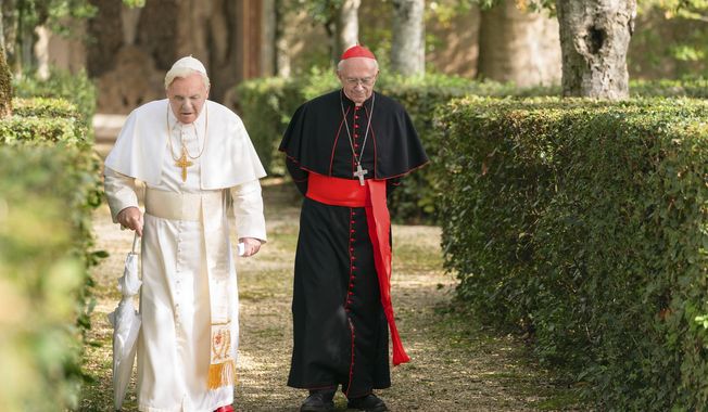 This image released by Netflix shows Jonathan Pryce as Cardinal Bergoglio, right, and Anthony Hopkins as Pope Benedict in a scene from &amp;quot;The Two Popes.&amp;quot; (Peter Mountain/Netflix via AP)