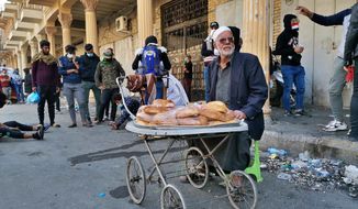 In this Tuesday, Nov. 26, 2019 photo, a street vendor sells cakes on Rasheed Street in Baghdad, Iraq. Baghdad’s Rasheed Street was the scene of large marches by Iraqis against British occupiers nearly a century ago and now it’s a front line in a new revolt. (AP Photo/Hadi Mizban)