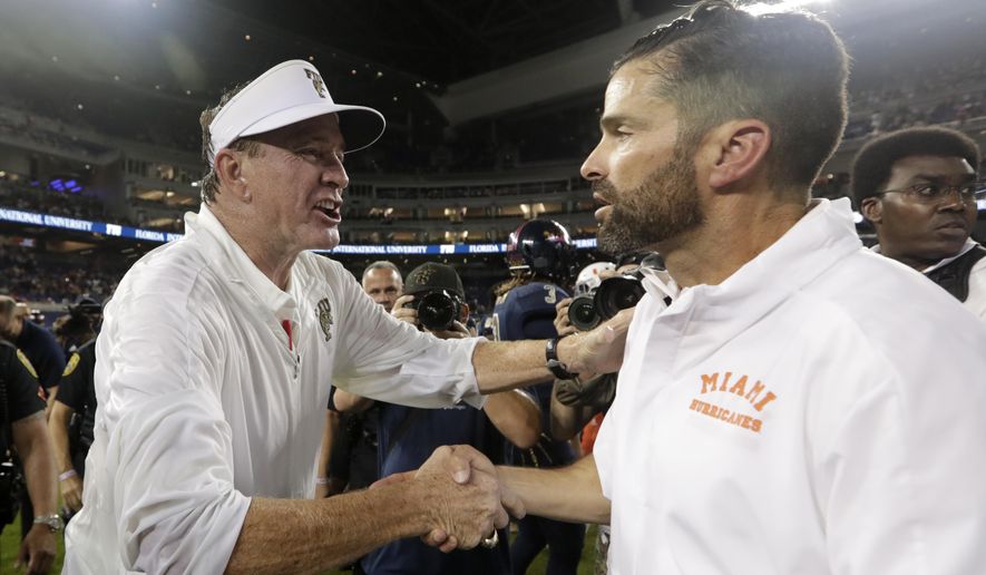 FIU head coach Butch Davis, left, shakes hands with Miami head coach Manny Diaz after an NCAA college football game, Saturday, Nov. 23, 2019, in Miami. FIU won 30-24. (AP Photo/Lynne Sladky)