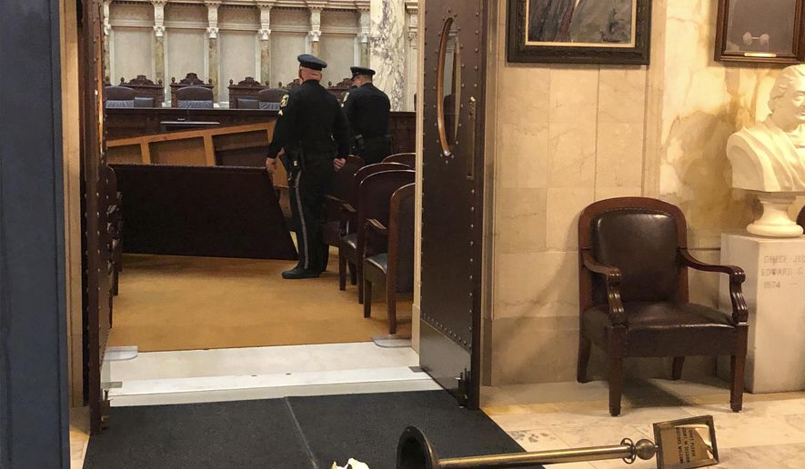 Wisconsin Capitol Police survey damage inside the state Supreme Court chamber in the Capitol after the man apparently toppled an ornate table on Tuesday, Nov. 26, 2019, in Madison, Wis. The court chamber was open to the public, but the Supreme Court was not present at the time of the incident. (AP Photo/Scott Bauer)