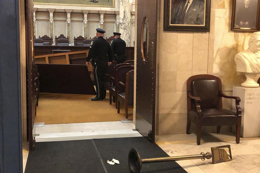 Wisconsin Capitol Police survey damage inside the state Supreme Court chamber in the Capitol after the man apparently toppled an ornate table on Tuesday, Nov. 26, 2019, in Madison, Wis. The court chamber was open to the public, but the Supreme Court was not present at the time of the incident. (AP Photo/Scott Bauer)