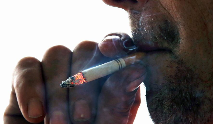 In this Nov. 6, 2014, file photo, a man smokes a cigarette on Main Street in Westminster, Mass.  (AP Photo/Elise Amendola), File