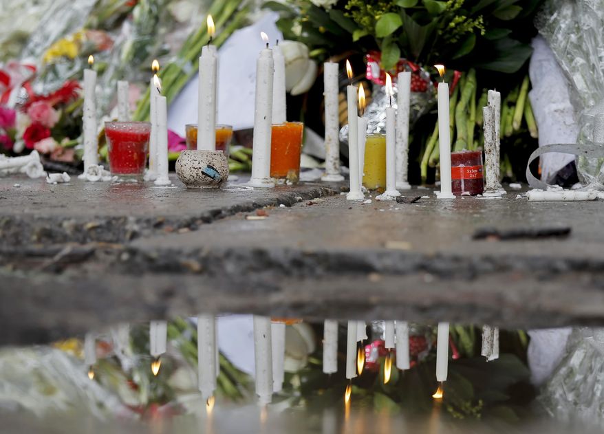 FILE - In this July 5, 2016, file photo, candles and flowers, offered in memory of victims of the attack on Holey Artisan Bakery, are reflected in a rainwater puddle in Dhaka, Bangladesh. A special tribunal in Bangladesh has sentenced seven members of a banned militant group to death for their involvement in an attack on a Dhaka cafe that more than 20 people. (AP Photo, File)