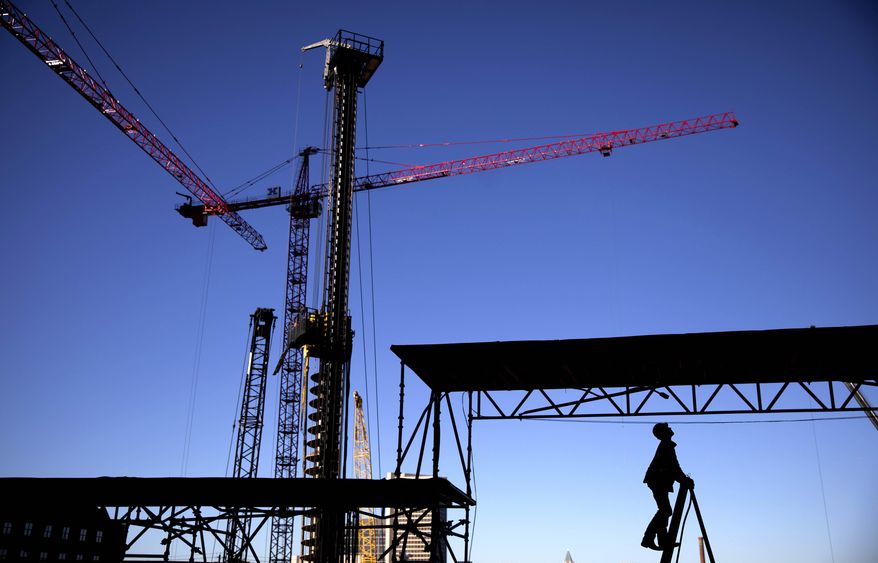 FILE - In this Oct. 23, 2019, file photo a worker climbs a ladder as cranes work the construction site for the new corporate headquarters of Norfolk Southern in Atlanta. On Wednesday, Nov. 27, the Federal Reserve releases its latest "Beige Book" survey of economic conditions. (AP Photo/David Goldman, File)
