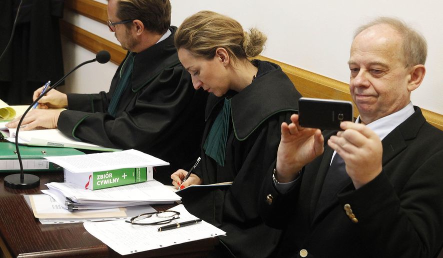Polish law professor of international renown, Wojciech Sadurski,right, in courtroom with his attorneys at the opening of a trial in which the ruling party Law and Justice is suing him for defamation over a 2018 tweet in which he called the party an "organized criminal group," at the Provincial Court in Warsaw, Poland, on Wednesday, Nov. 27, 2019. Sadurski said he acted in public interest when he expressed his private view that the party's policies break Poland's legal order. The court's verdict is expected Dec. 16. (AP Photo/Czarek Sokolowski)
