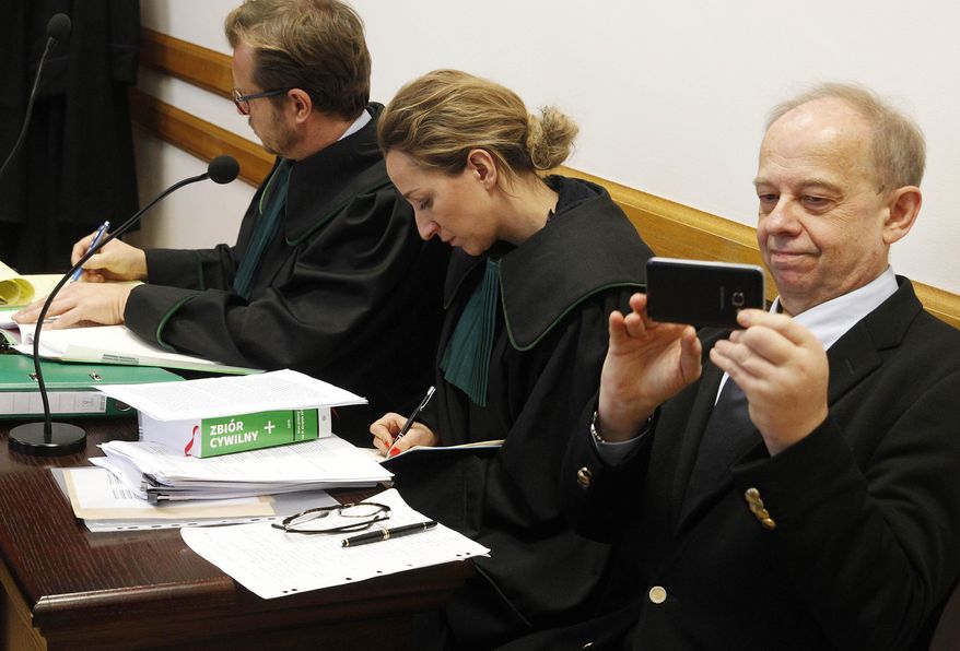 Polish law professor of international renown, Wojciech Sadurski,right, in courtroom with his attorneys at the opening of a trial in which the ruling party Law and Justice is suing him for defamation over a 2018 tweet in which he called the party an "organized criminal group," at the Provincial Court in Warsaw, Poland, on Wednesday, Nov. 27, 2019. Sadurski said he acted in public interest when he expressed his private view that the party's policies break Poland's legal order. The court's verdict is expected Dec. 16. (AP Photo/Czarek Sokolowski)