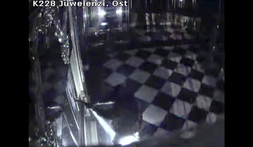 This photo taken from a video of a CCTV camera shoes a person in black clothes, center, destroying display cases with jewels inside theGreen Vault in Dresden, Germany, early Monday Nov. 25, 2019. Thieves broke into Dresden’s Green Vault early Monday morning, making off with three sets of jewelry from the 18th century that German officials said would be impossible to sell on the open market. (Police Saxony/dpa via AP)