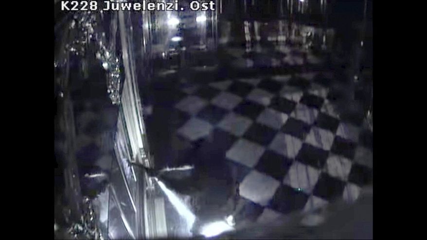 This photo taken from a video of a CCTV camera shoes a person in black clothes, center, destroying display cases with jewels inside theGreen Vault in Dresden, Germany, early Monday Nov. 25, 2019. Thieves broke into Dresden’s Green Vault early Monday morning, making off with three sets of jewelry from the 18th century that German officials said would be impossible to sell on the open market. (Police Saxony/dpa via AP)