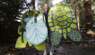 In this photo taken Monday, Nov. 25, 2019, Lisa Wathne holds original sea turtle costumes, like the one she wore 20 years earlier that were made for protesters at the World Trade Organization (WTO) demonstrations in Seattle, in Lake Forest Park, Wash. Wathne and other demonstrators wore the cardboard turtle shells to protest WTO policies, including one interpreted by protesters as disregarding the plight of turtles killed by shrimp nets. A wide array of issues brought tens of thousands of protesters to Seattle 20 years ago Saturday, with one unifying theme: concern that the World Trade Organization, a then-little-known body charged with regulating international trade, threatened them all. (AP Photo/Elaine Thompson)