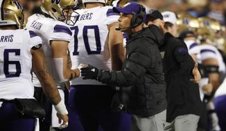 Washington quarterback Jacob Eason, left, confers with coach Chris Petersen during the first half of the team&#x27;s NCAA college football game against Colorado on Saturday, Nov. 23, 2019, in Boulder, Colo. (AP Photo/David Zalubowski)
