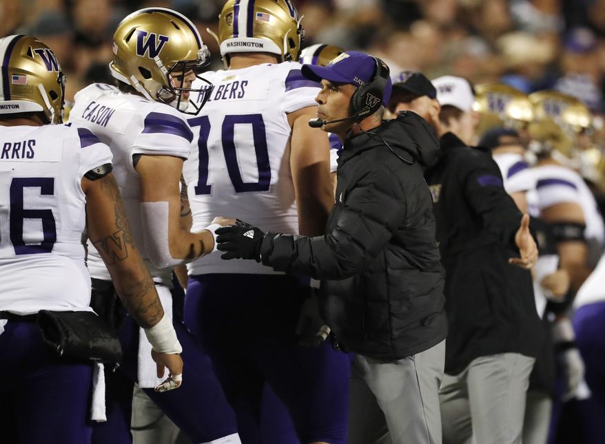 Washington quarterback Jacob Eason, left, confers with coach Chris Petersen during the first half of the team&#39;s NCAA college football game against Colorado on Saturday, Nov. 23, 2019, in Boulder, Colo. (AP Photo/David Zalubowski)
