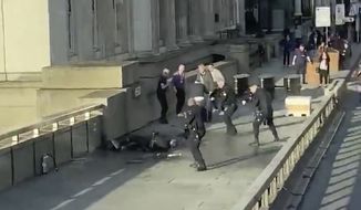 In this grab taken from video made available by @HLOBlog, a man is surrounded by police after an incident on London Bridge, in London, Friday, Nov. 29, 2019. A man wearing a fake explosive vest stabbed several people before being tackled by members of the public and then shot dead by armed officers on London Bridge, police and the citys mayor say. Police say they are treating it as a terrorist attack. (@HLOBlog via AP)