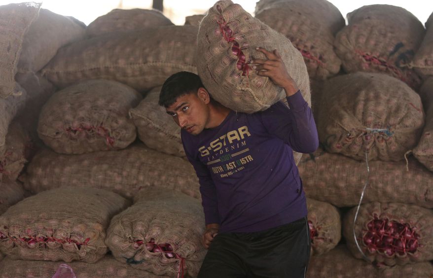 An Indian laborer carries a sack of onions at a wholesale market on the outskirts of Jammu, India, Friday, Nov. 29, 2019. India’s economic growth has slipped to 4.5%, the slowest annual pace in six years, in the July-September quarter with labor-intensive manufacturing sector registering a negative growth. (AP Photo/Channi Anand)