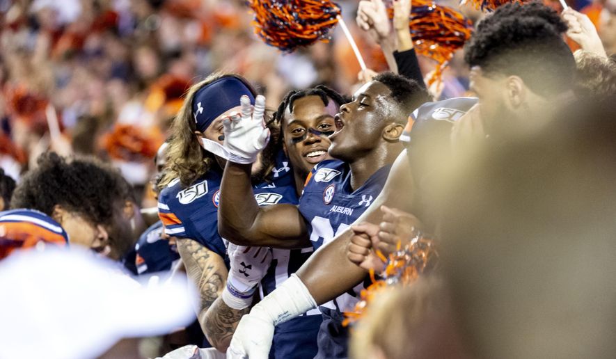 Auburn players sit in the student section as fans take the field to celebrate an upset of Alabama after an NCAA college football game, Saturday, Nov. 30, 2019, in Auburn, Ala. (AP Photo/Vasha Hunt)
