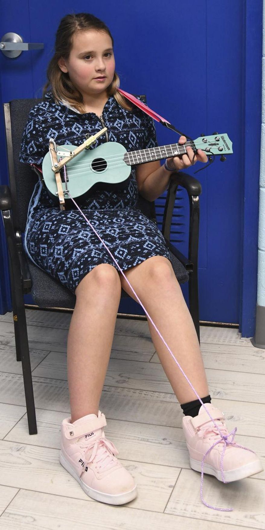 In this Nov. 19, 2019, photo Savannah Griffith, 11, a fifth-grader at Poage Elementary School in Ashland, Ky., plays ukulele at school using a device built by her teacher&#39;s husband. (Kevin Goldy/The Daily Independent via AP)