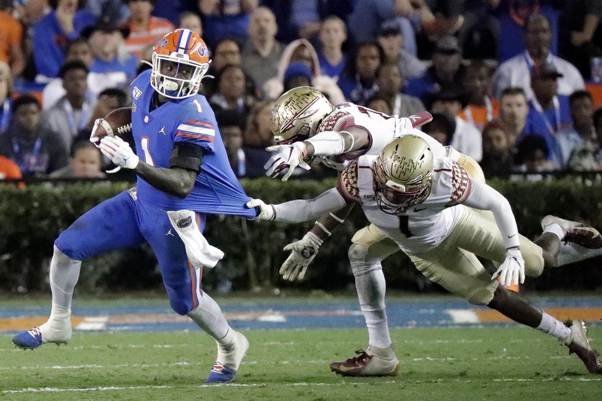 Florida wide receiver Kadarius Toney, left, tries to escape the grasp of Florida State defensive back Levonta Taylor, back right, during the first half of an NCAA college football game Saturday, Nov. 30, 2019, in Gainesville, Fla. (AP Photo/John Raoux)