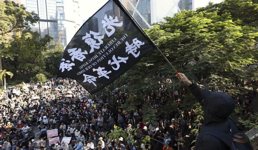 A protester waves a flag reading "Liberate Hong Kong, the Revolution of Our Times" during a rally for students and elderly pro-democracy demonstrators in Hong Kong, Saturday, Nov. 30, 2019. Hundreds of Hong Kong pro-democracy activists rallied Friday outside the British Consulate, urging the city's former colonial ruler to emulate the U.S. and take concrete actions to support their cause, as police ended a blockade of a university campus after 12 days. (AP Photo/Ng Han Guan)