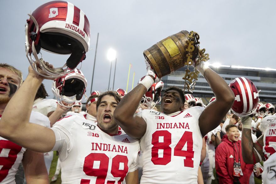 Indiana tight end Turon Ivy Jr. (84) and place kicker Nathanael Snyder (99) celebrate with the Old Oaken Bucket following an NCAA college football game against Purdue in West Lafayette, Ind., Saturday, Nov. 30, 2019. Indiana defeated Purdue 44-41 in double overtime. (AP Photo/Michael Conroy)